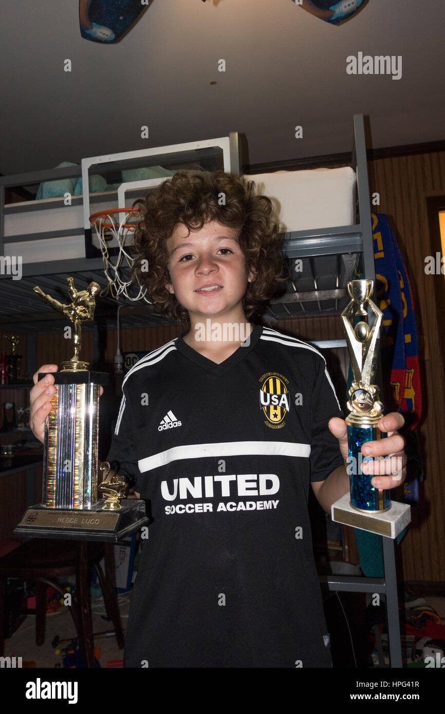 Orgulloso joven jugador de fútbol de 12 años de edad la celebración de dos grandes trofeos ganados por sus esfuerzos atléticos. Downers Grove, Illinois IL USA Foto de stock