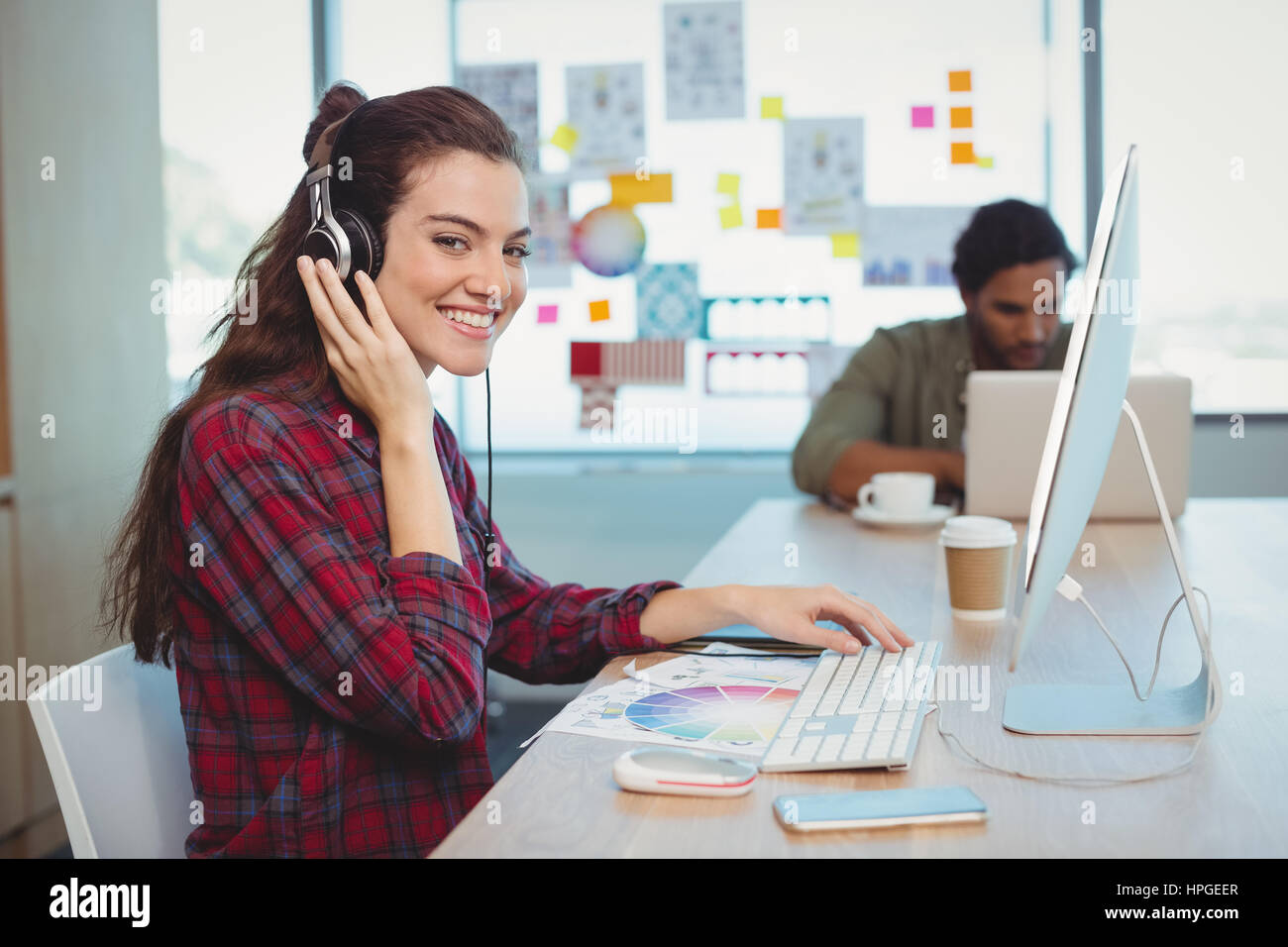 Diseñador gráfico femenino trabajando mientras escucha música en la oficina Foto de stock