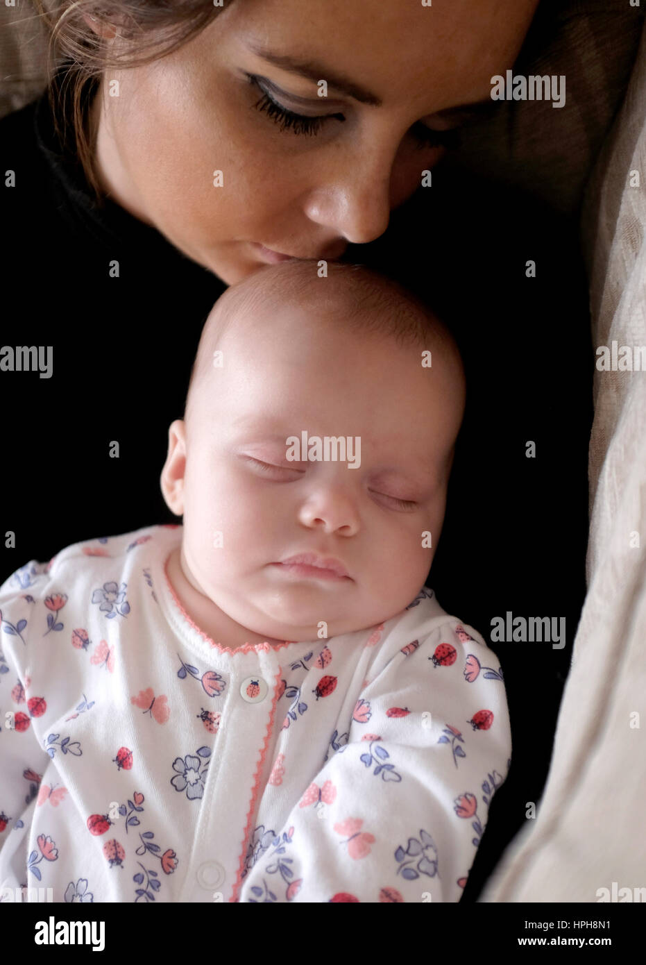 La joven madre y su bebé dormido caricias Foto de stock