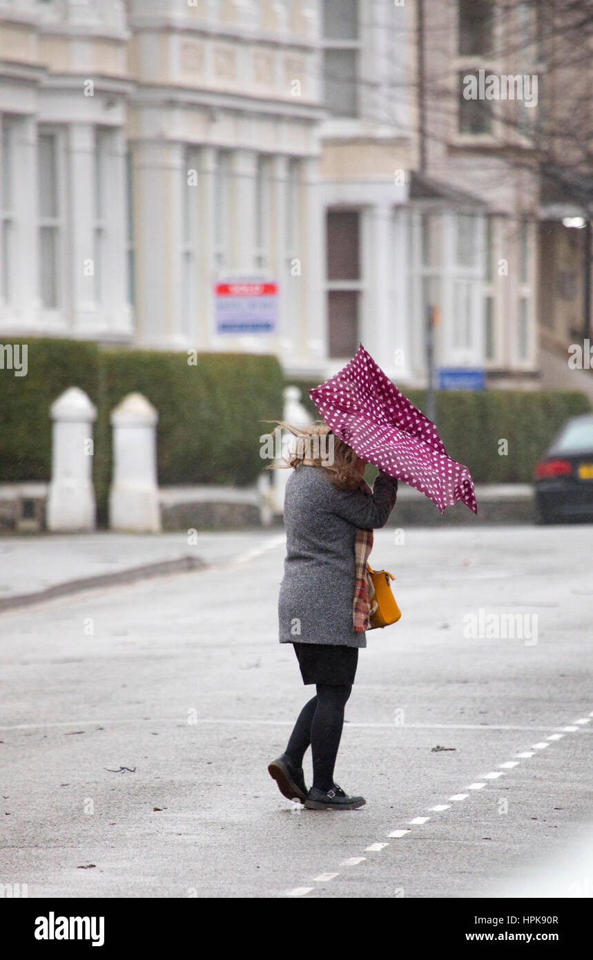 Hembra commuter caminando al trabajo en húmedo y ventoso clima como consecuencia de la tormenta Doris como impactó en Llandudno, Gales del Norte Foto de stock