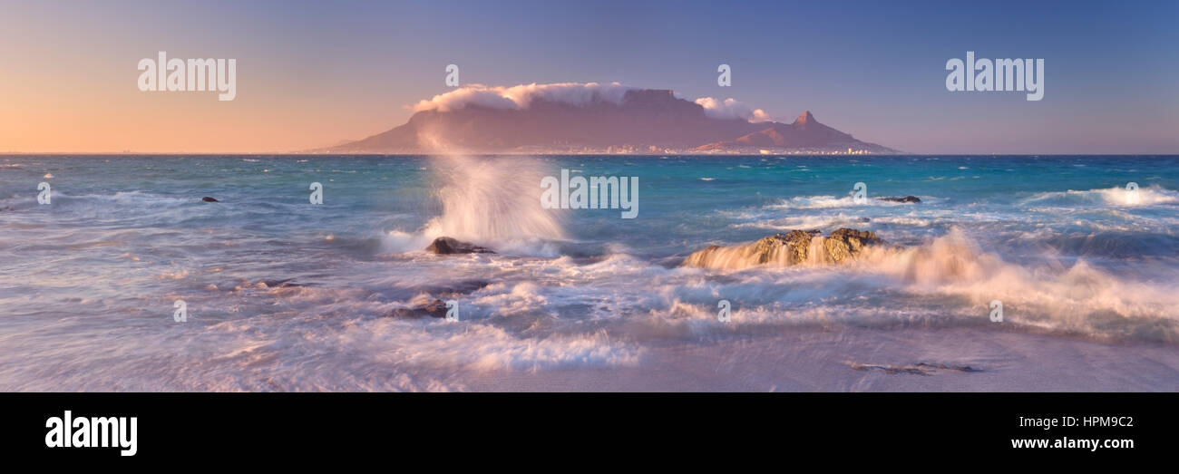 Amanecer sobre la montaña Table y Ciudad del Cabo, desde la playa de Bloubergstrand. Foto de stock