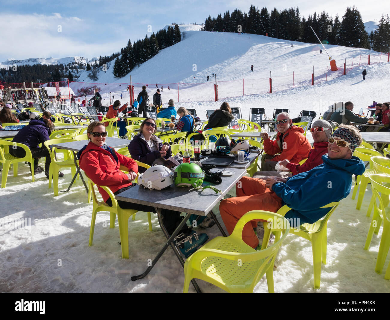 Familiares y amigos de los esquiadores en invierno vacaciones disfrutando del sol restaurantes fuera de un restaurante de esquí en los Alpes franceses. Samoens Ródano-Alpes Francia Europa Foto de stock