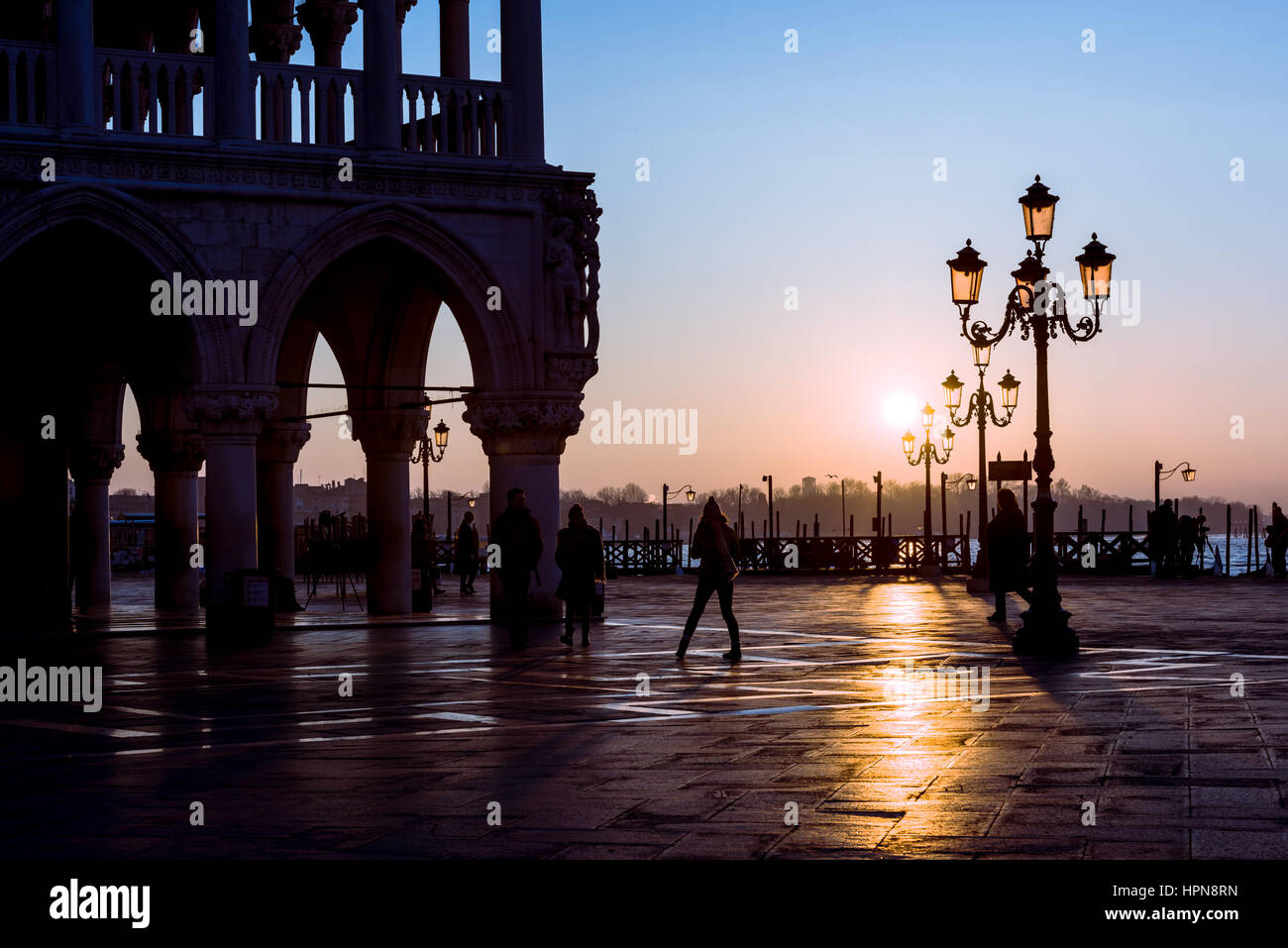 El sol se levanta por detrás de las luces en la plaza de San Marcos en Venecia. Al lado puede verse el contorno del Palacio Ducal Foto de stock