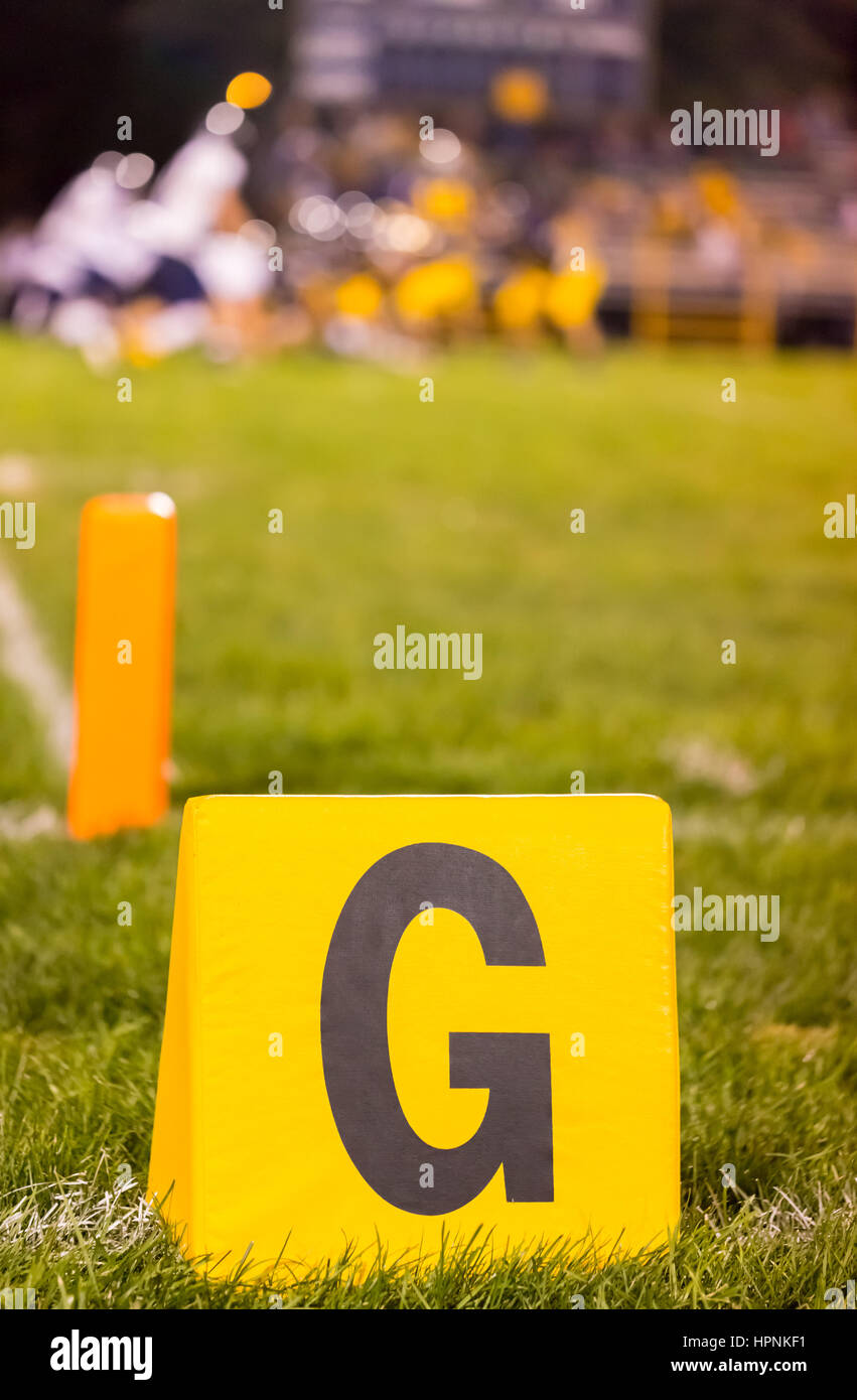 Fútbol americano amarillo línea objetivo marcador en el ámbito escolar con el estudiante atletas en el campo Foto de stock