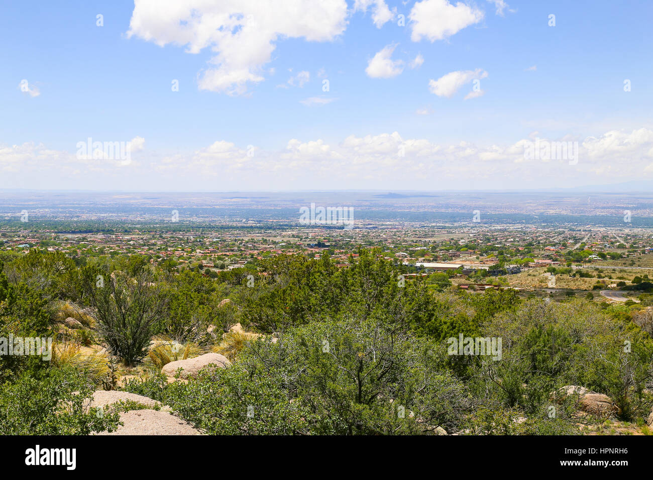 Vista panorámica de Albuquerque, EE.UU., desde el punto de partida de Sandia Peak Tramway, en primer plano, las rocas y los matorrales. Foto de stock