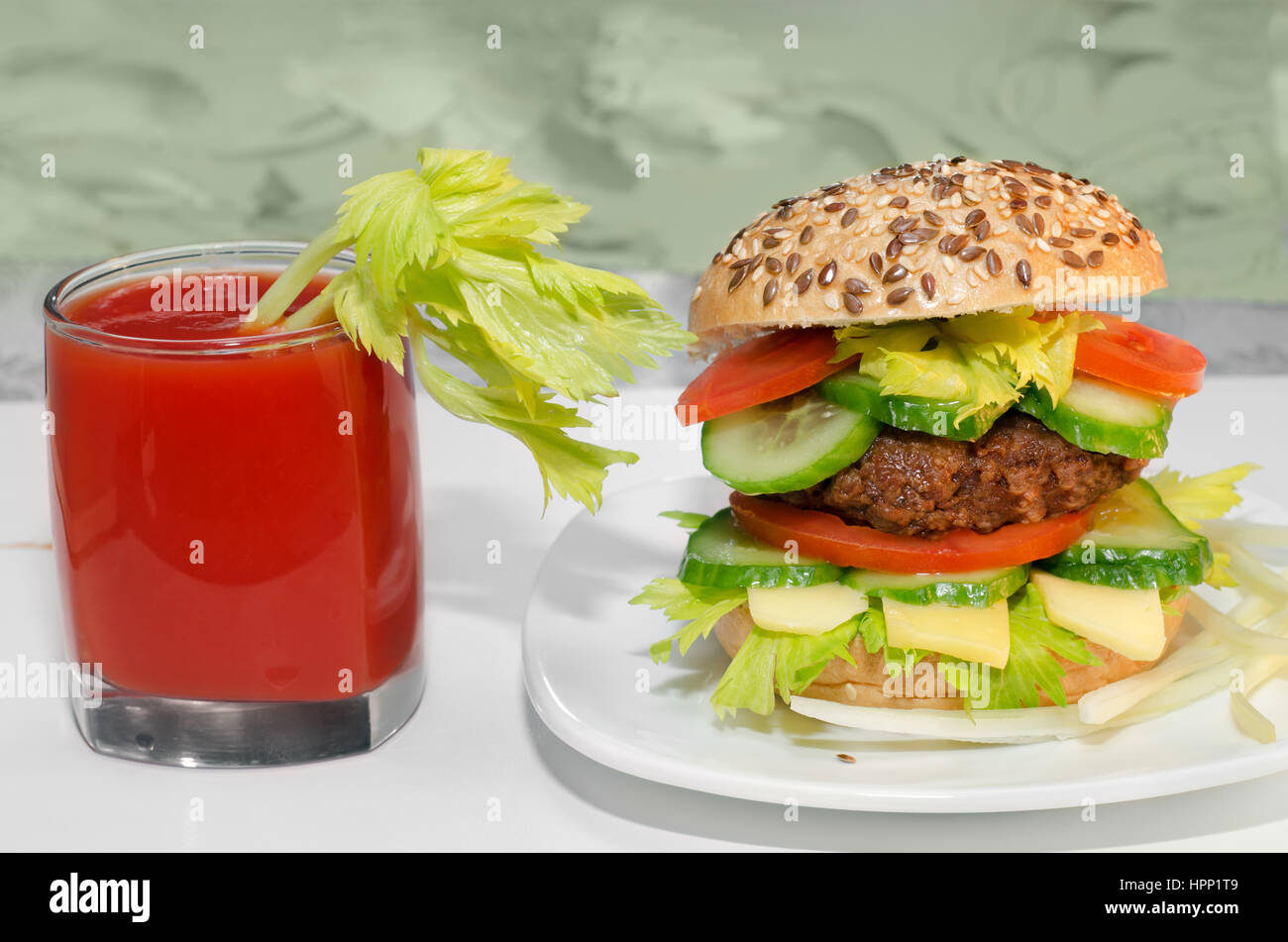 Gran Burger y el jugo de tomate con el apio en el vaso. Foto de stock