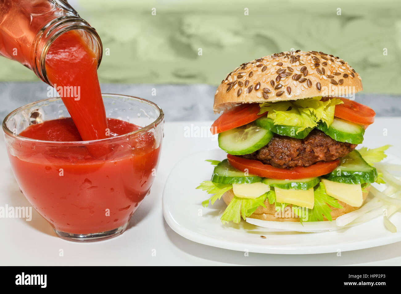 Gran hamburguesa y zumo de tomate se vierte en un vaso. Taza Foto de stock