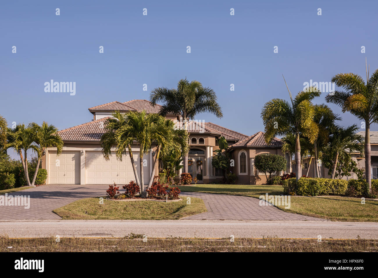 El suroeste de Florida típico de bloque de hormigón de estuco y casa en el campo, con palmeras, plantas tropicales y flores, césped y pinos. f Foto de stock