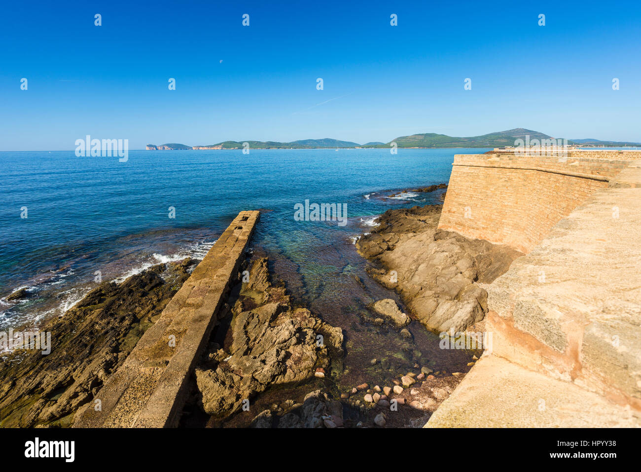 Vista de Capo Caccia desde el paseo marítimo a lo largo de las murallas de la ciudad de Alghero, Sassari, Cerdeña, Italia Foto de stock