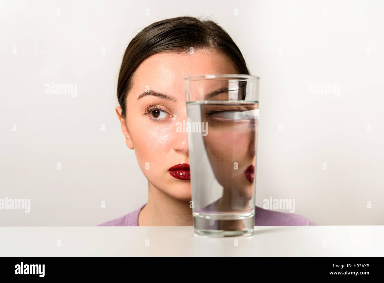 Las mujeres enfrentan la distorsión en el vaso de agua Foto de stock
