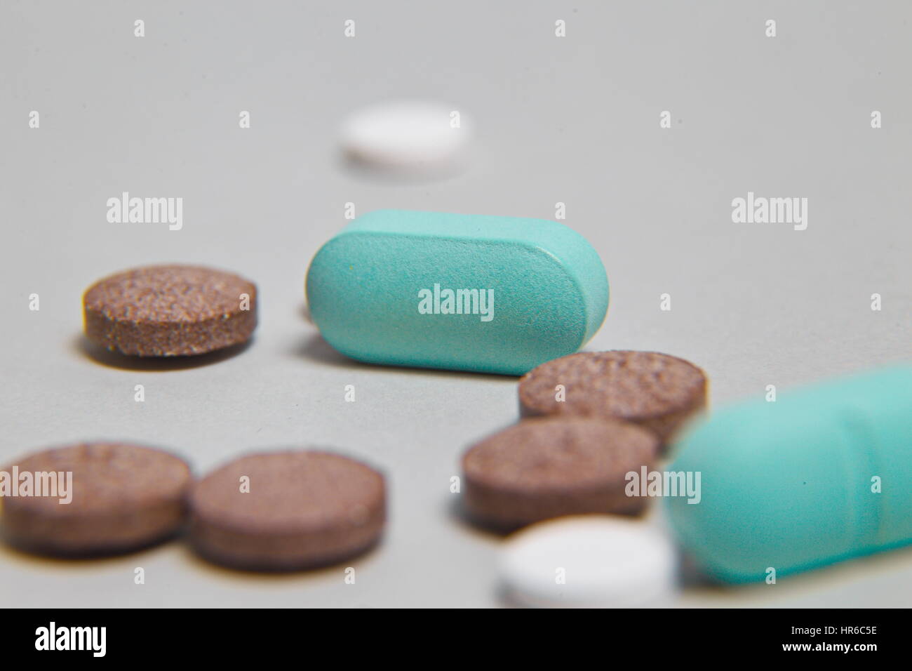 Montón de píldoras azules con inyección de color verde en el fondo. Herramientas médicas. Foto de stock