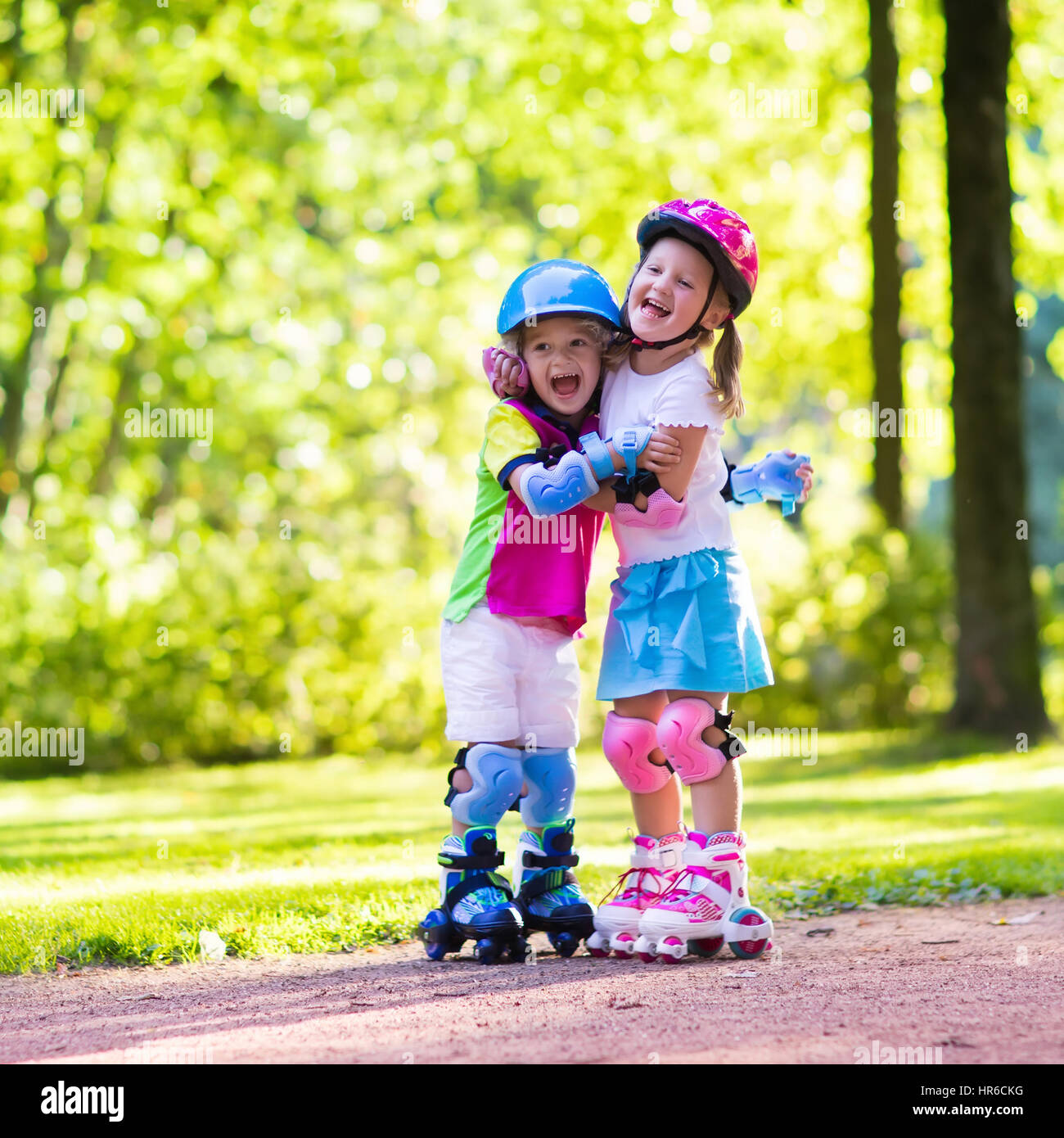 Niños y niñas aprenden a roller skate park en verano. Niños vestidos almohadillas de protección y casco de seguridad para patinar seguro viaje. Outdoor Activo spo Foto de stock