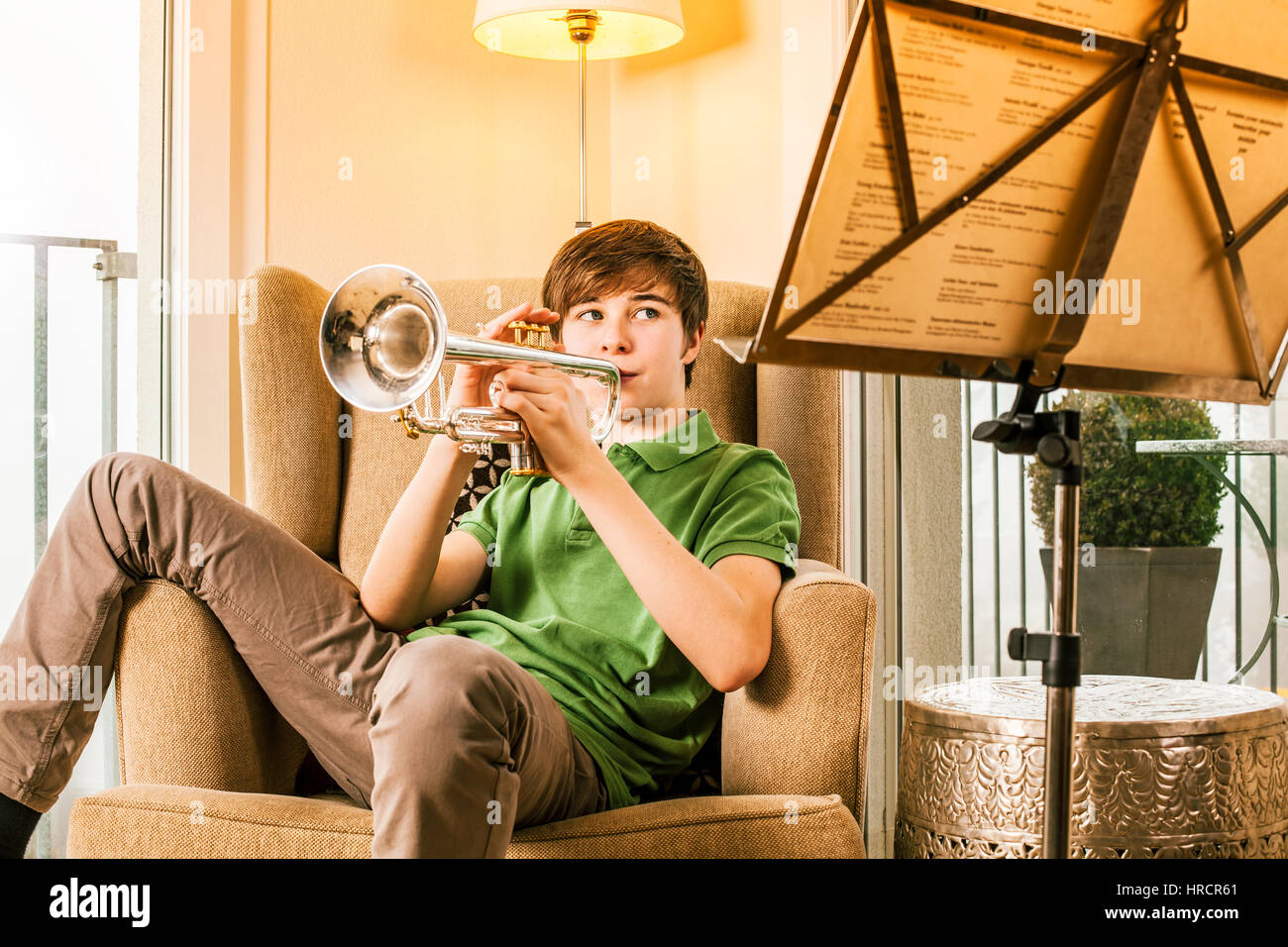 Foto de un varón adolescente practicando su trompeta en casa. Foto de stock