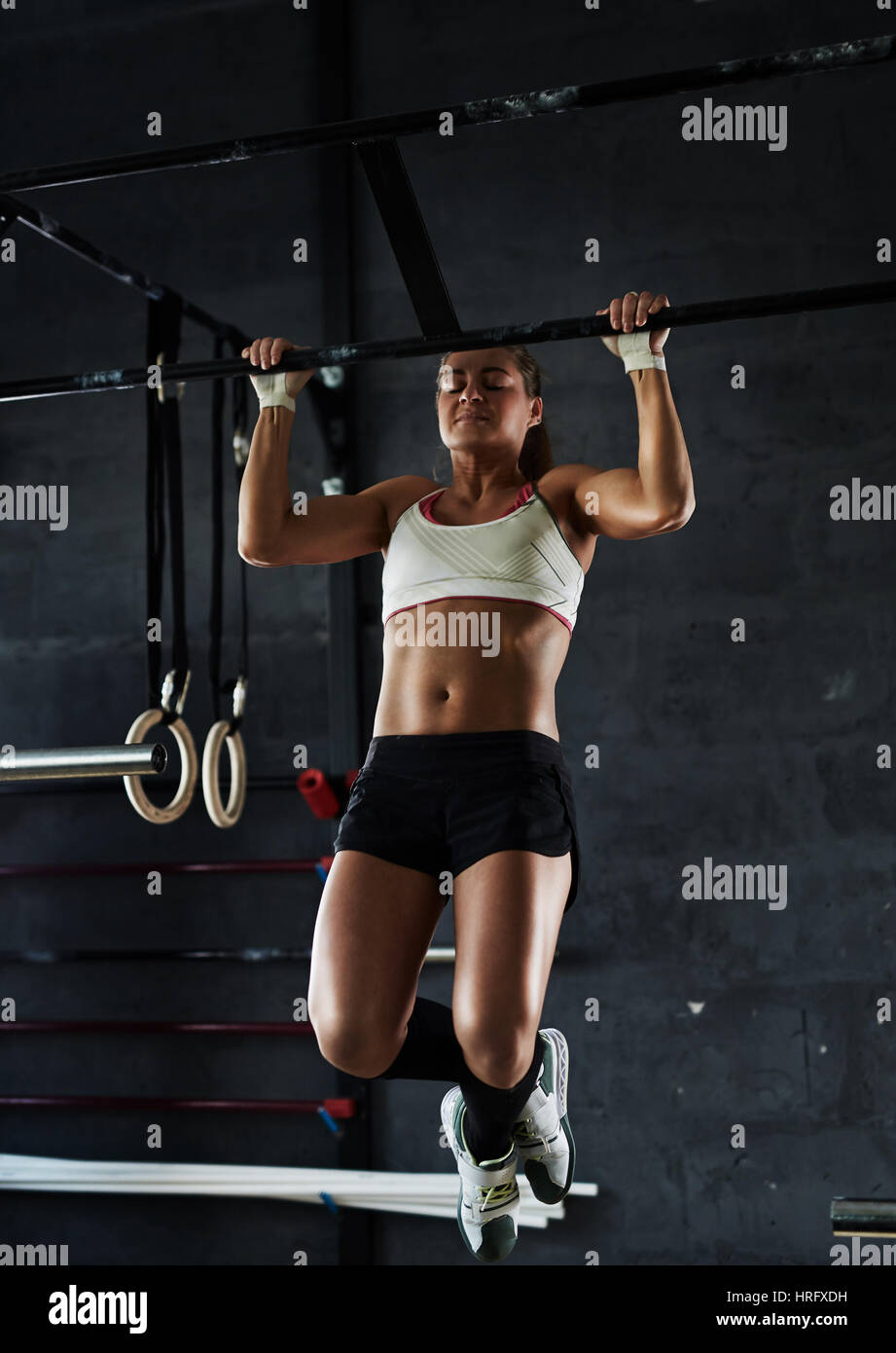 Un intenso entrenamiento en el gimnasio crossfit oscuro: fuerte mujer  deportiva realizar pull-ups en la barra de pared Fotografía de stock - Alamy