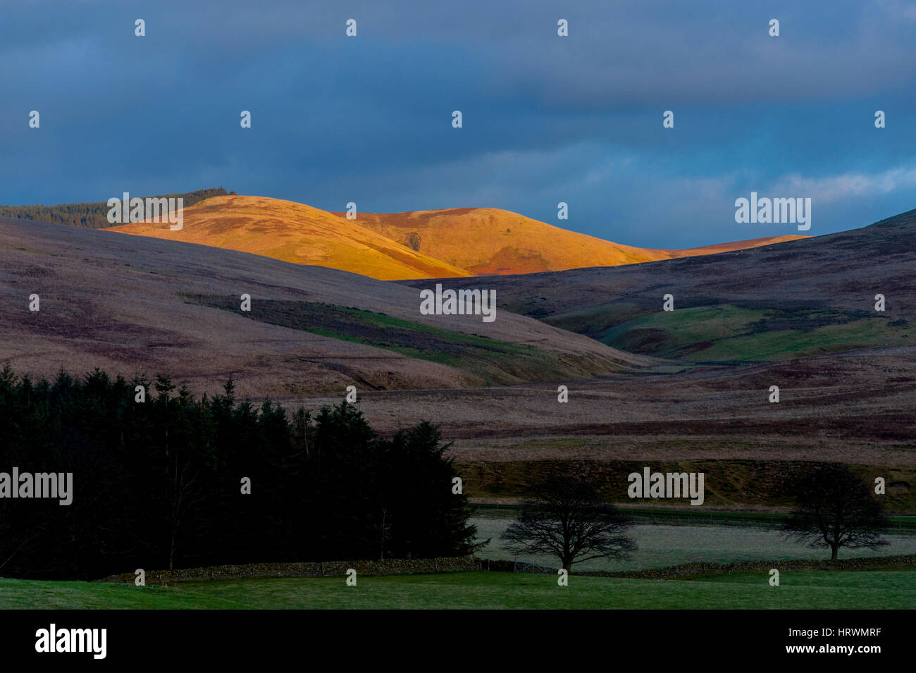 Las colinas cerca de Abington en las tierras altas meridionales de Escocia. Con el sol tan solo tocar las cimas de las colinas en la distancia al atardecer. Foto de stock