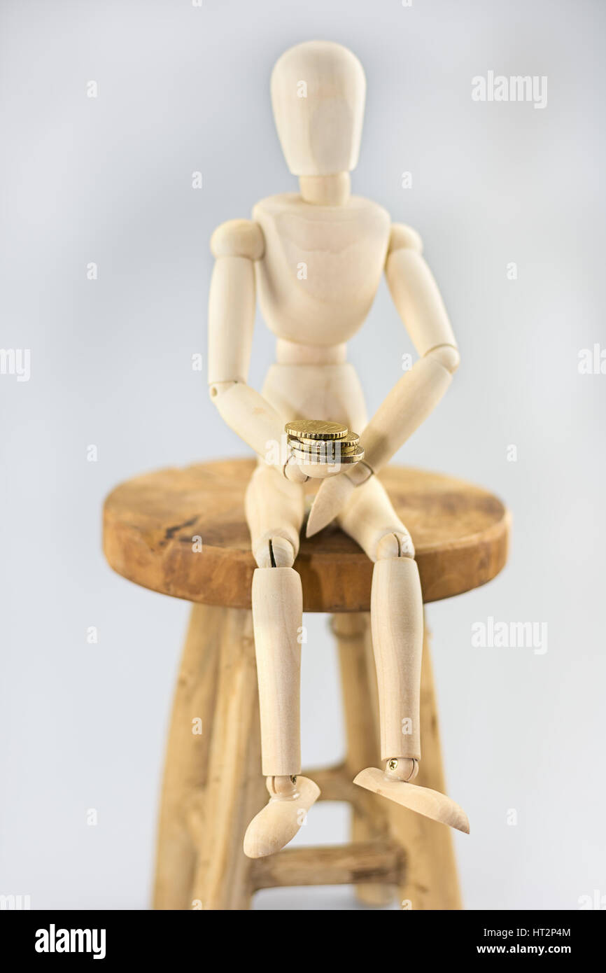 Maniquí sentado en una silla y sosteniendo una moneda. Foto de stock