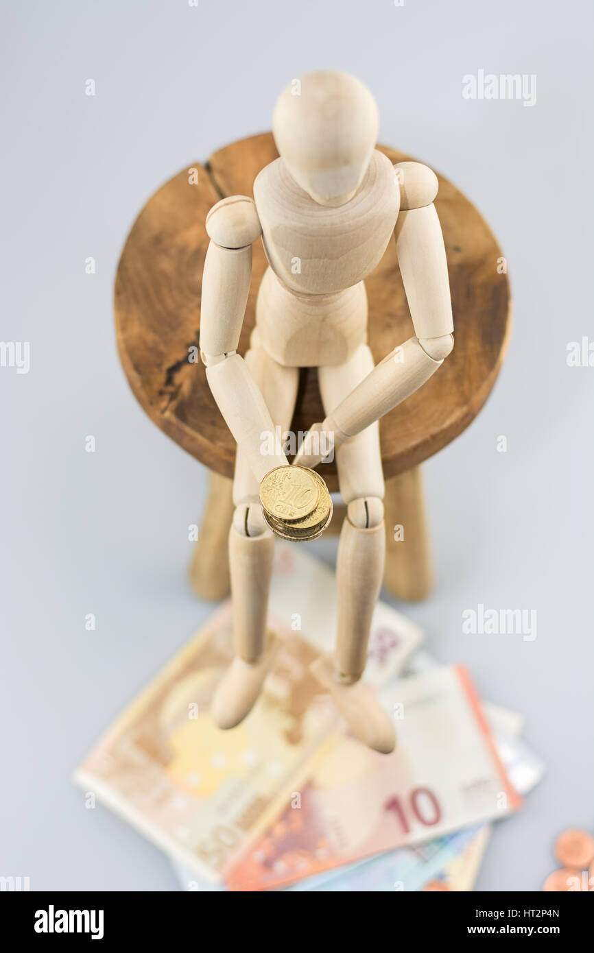 Maniquí sentado en una silla y sosteniendo una moneda. Foto de stock