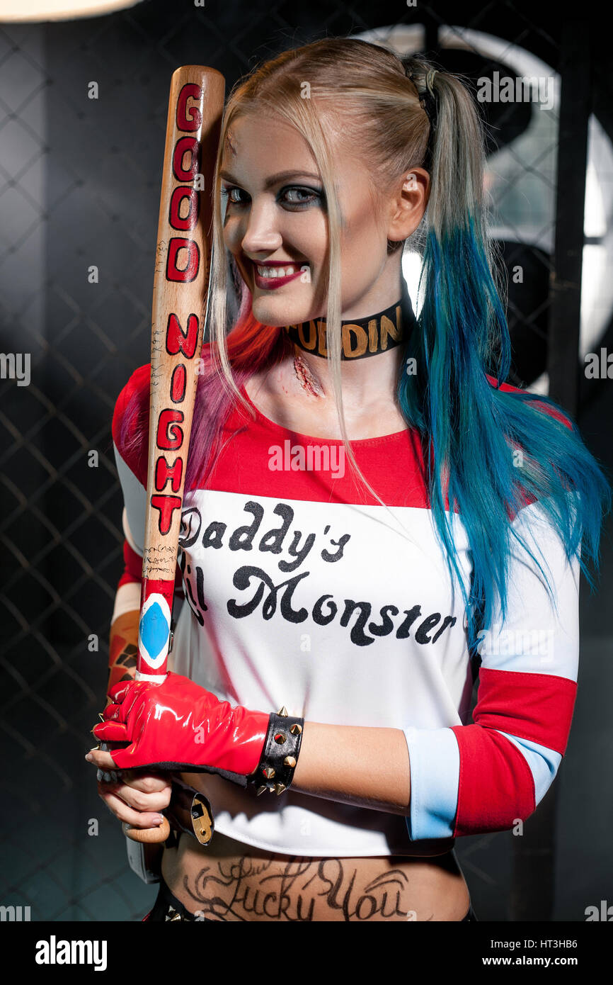 Retrato de niña sonriente en traje de Harley Quinn. Ella se levanta con un  murciélago. Ella está cerca de cuadrícula. Cerca. Cosplay Fotografía de  stock - Alamy