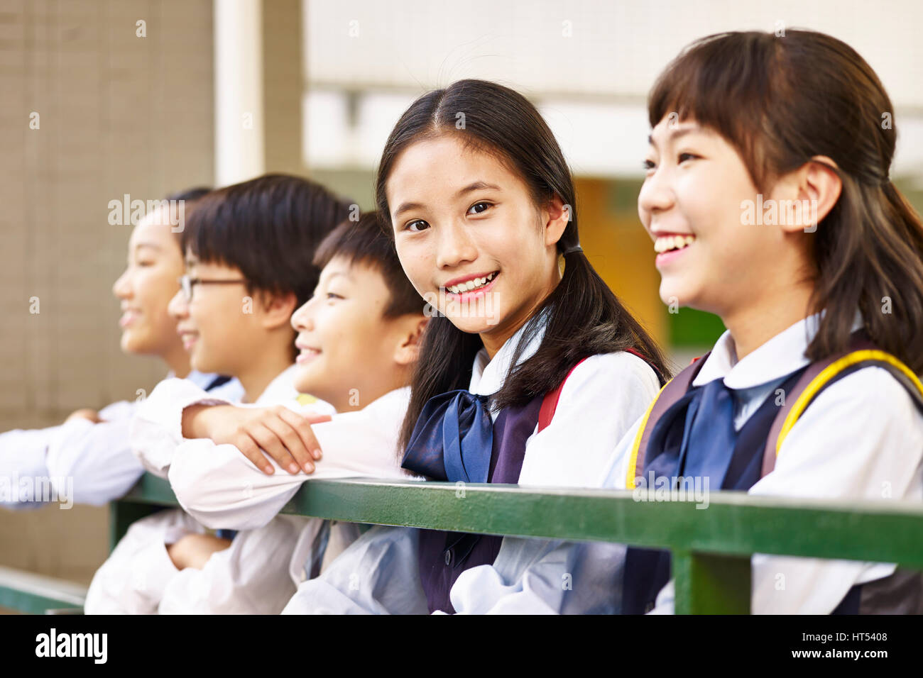 Grupo de niños de escuela primaria con una colegiala mirando a la cámara sonriendo. Foto de stock