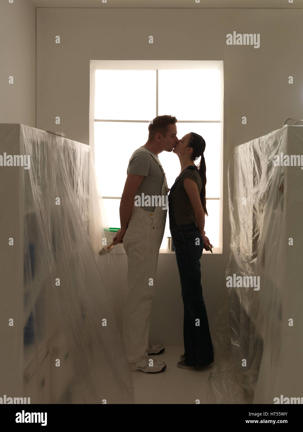 Feliz pareja besándose en su nuevo hogar listo para redecorar diy Foto de stock
