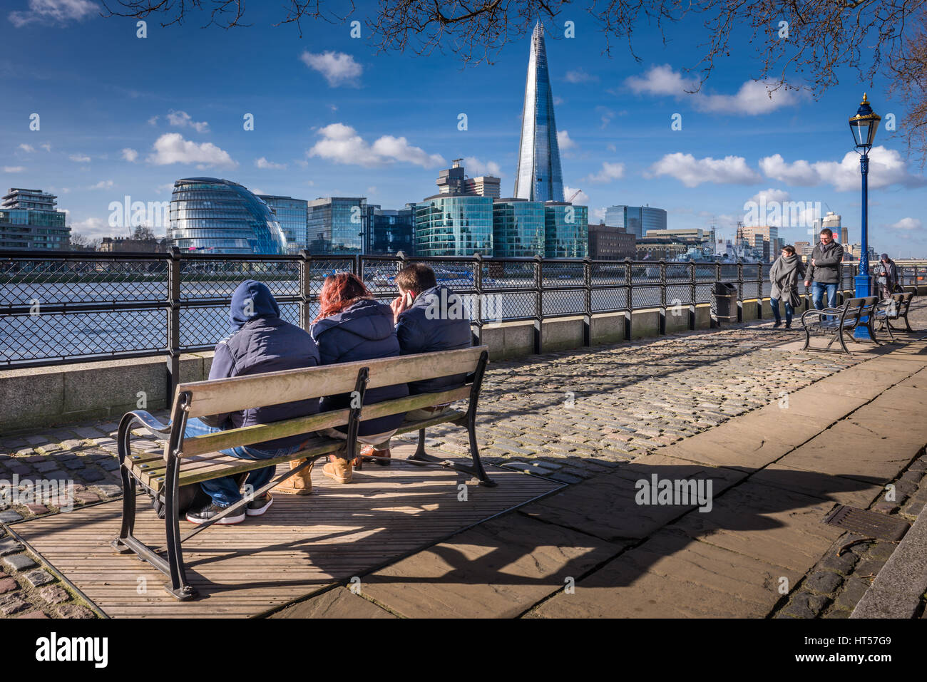 La gente disfruta del sol en el camino fuera de la Torre de Londres en un día frío, pero brillante en la ciudad capital de Londres. Foto de stock