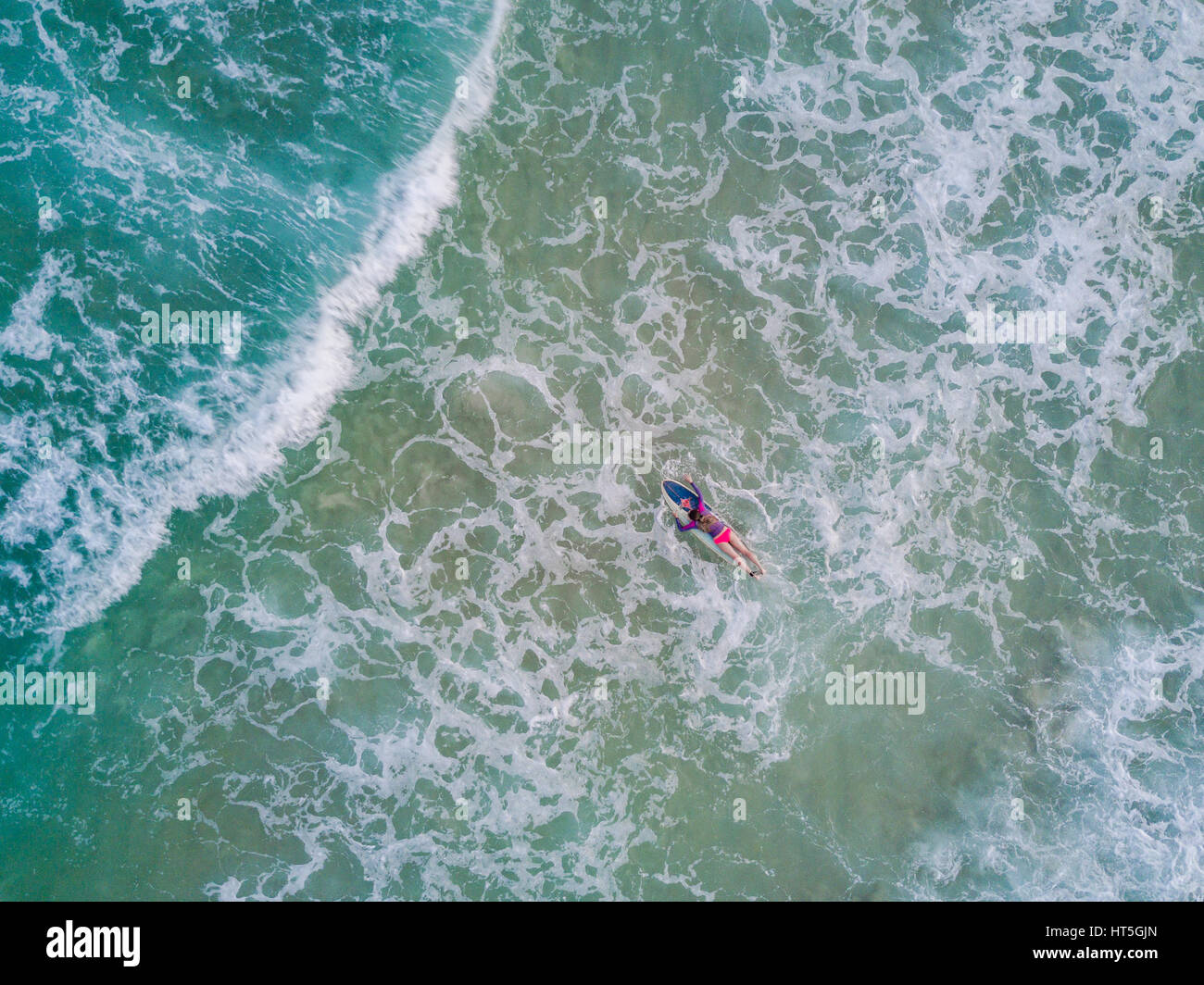 Surfer palas hembra a través de la descomposición del agua en Tai Wan Long Beach, Hong Kong. Foto de stock