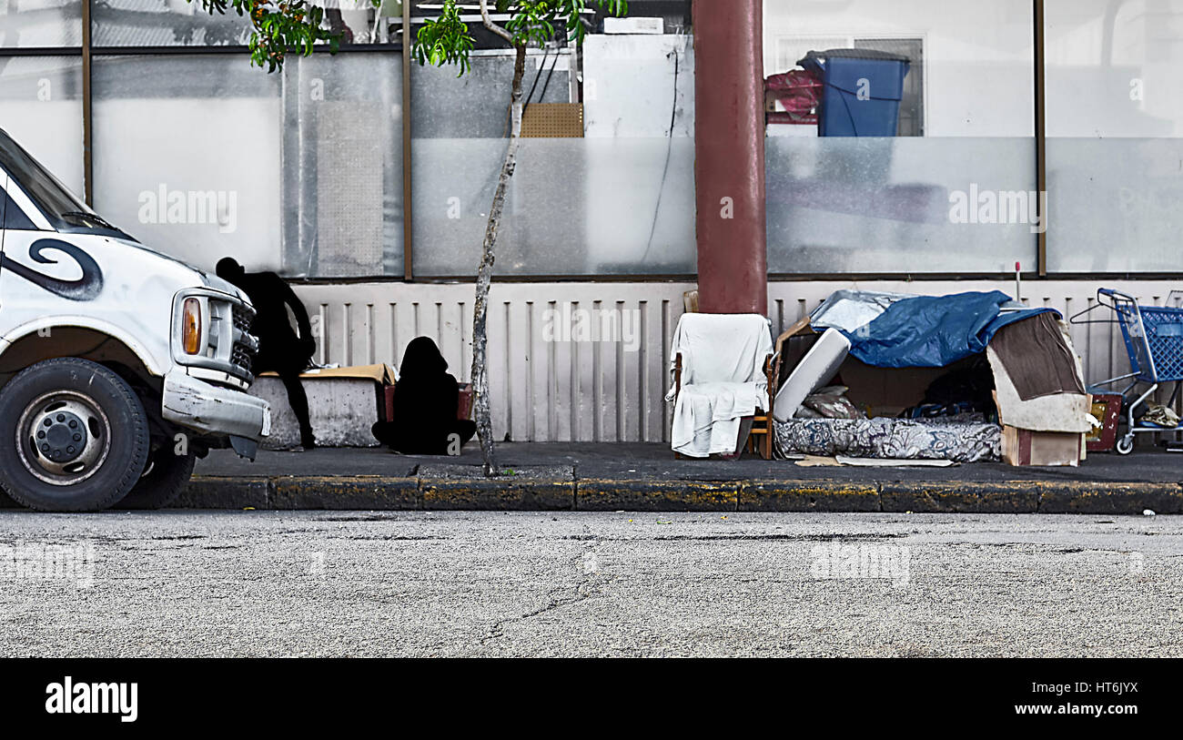 Sombra sin hogar no identificado cifras sobre una acera interior de la ciudad, cerca de una vivienda sin hogar y calle van Foto de stock