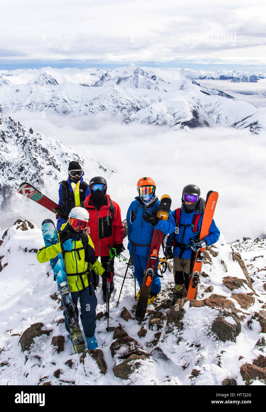 Un grupo de cinco esquiadores de pie en una cresta rocosa delante de la majestuosa cordillera de Los Andes Foto de stock