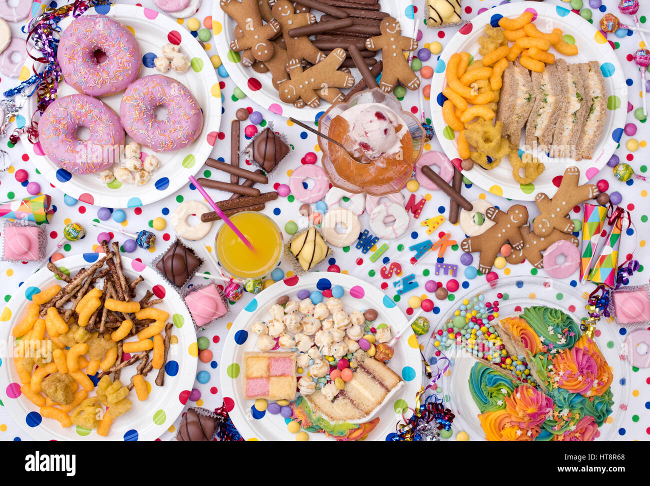 Fiesta infantil alimentos incluyendo sándwiches, pasteles, gelatinas y helados, galletas, papas fritas, caramelos y rosquillas en un fondo de lunares. Patrón Foto de stock