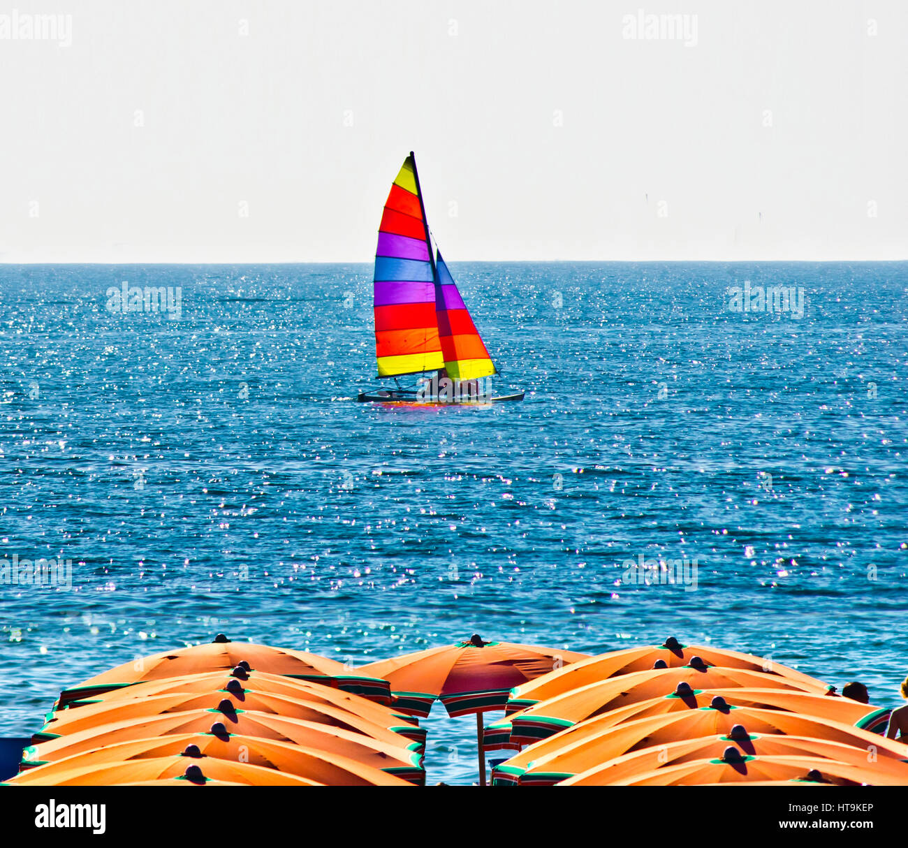 Barco en el mar con fondo naranja paraguas en verano con un cielo azul Foto de stock