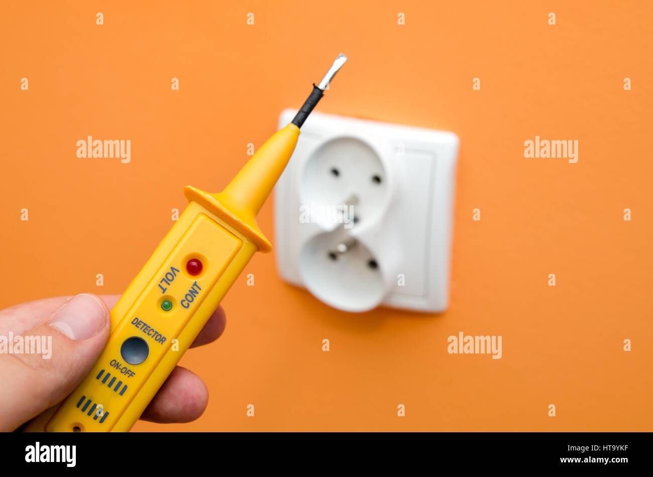 Medidor de corriente eléctrica, girar el tornillo cercano a la toma de  pared de color naranja Fotografía de stock - Alamy