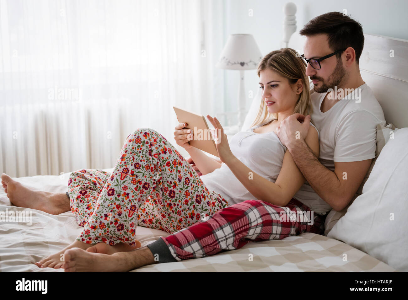 Pareja feliz en el amor con tablet en pijama en casa Fotografía de stock -  Alamy