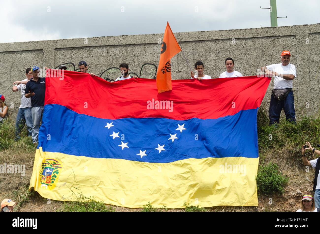 Un grupo de opositores al gobierno venezolano, sostiene una bandera de Venezuela en retroceso, como una solicitud de emergencia internacional. Foto de stock