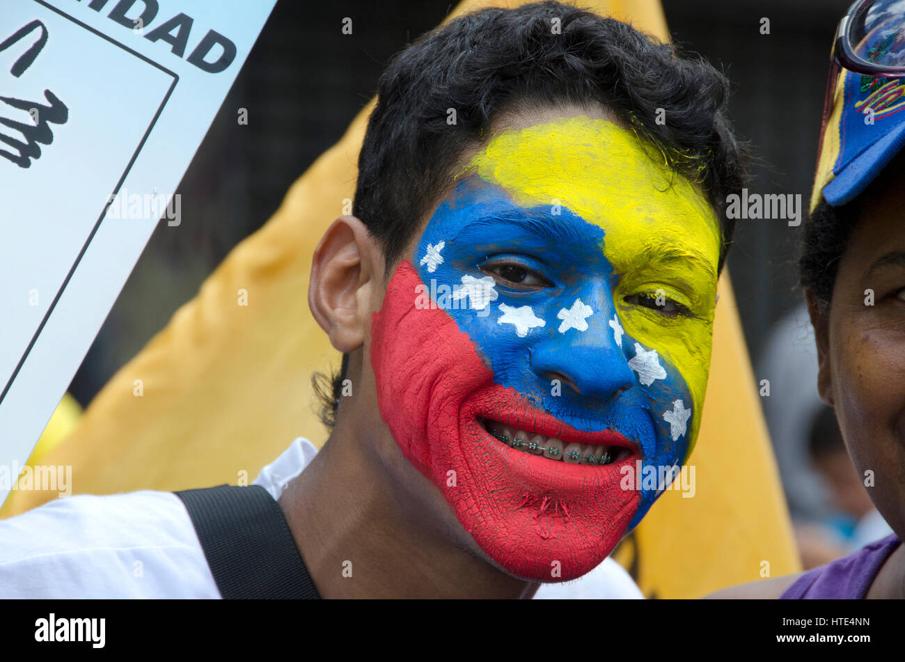 Un hombre joven con la cara pintada con la bandera de Venezuela, participa en una marcha contra el gobierno de Venezuela Foto de stock