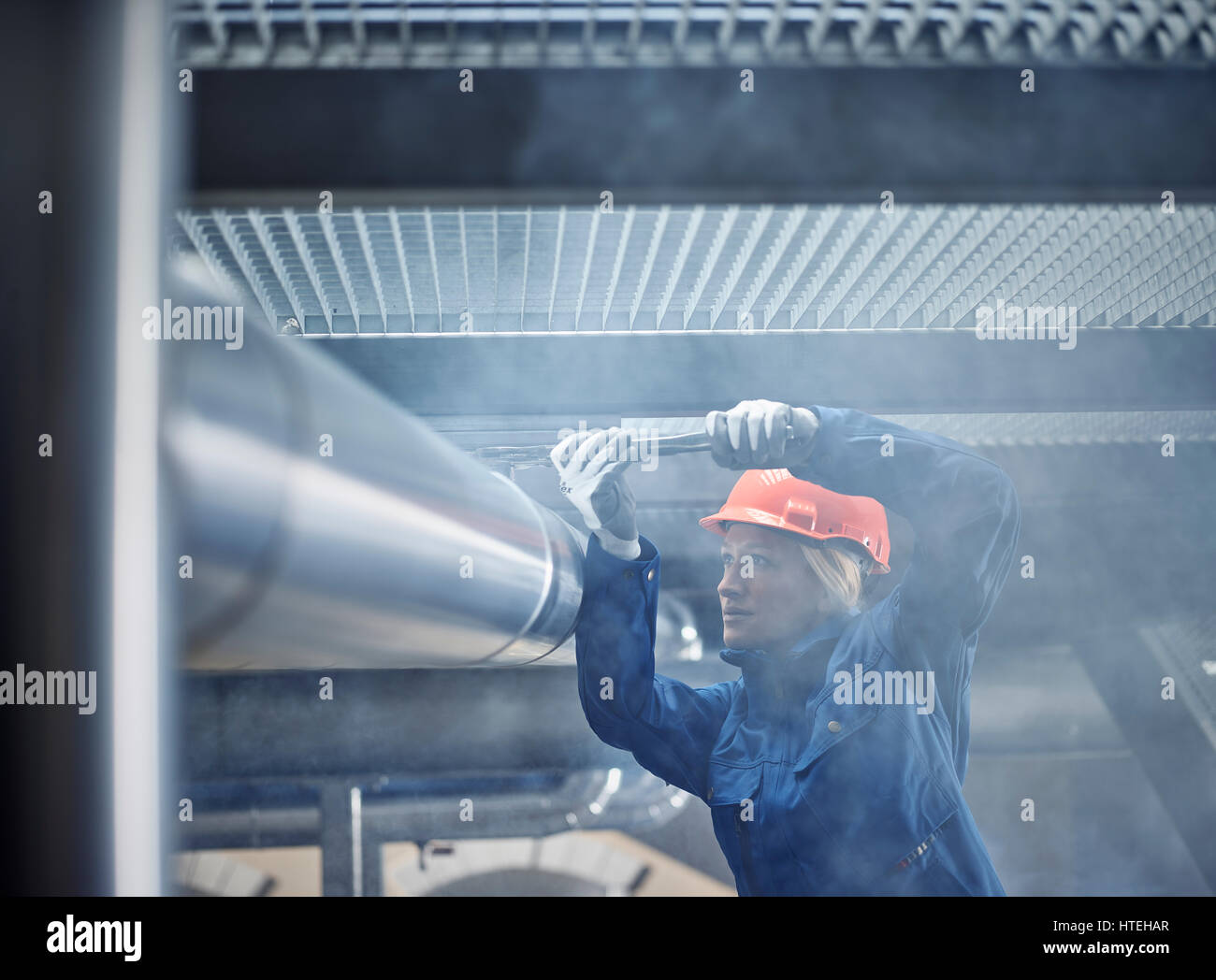 Técnico mecánico con casco de naranja el montaje de un soporte de la línea de refrigeración, Austria Foto de stock