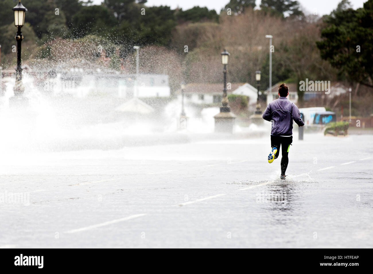 Un corredor correr a través de los charcos de agua de tormenta profunda ejecutar splash fitness salud adverso clima inclemente viento húmedo de compromiso spray sport undetered jog Foto de stock