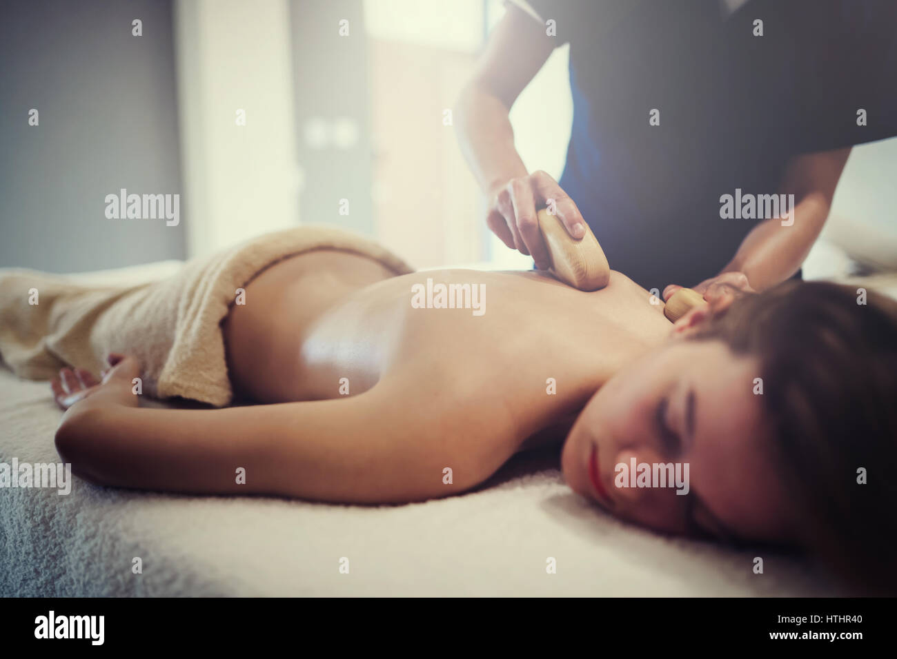 Masaje masajista femenino en la cama mientras ella se relaja Foto de stock