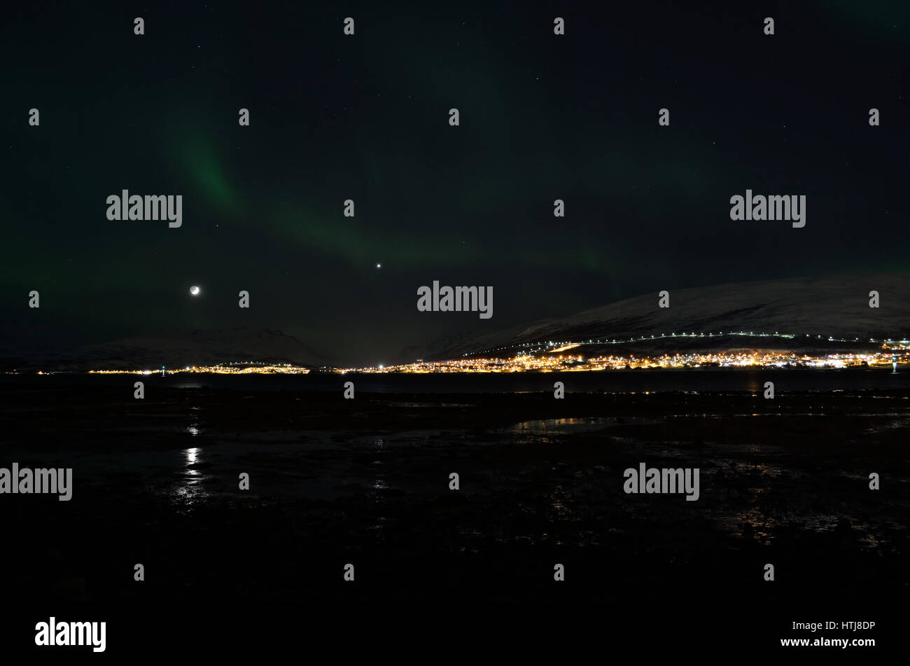 Aurora Borealis bailar sobre montaña nevada y fiordo paisaje con la luz de la luna llena Foto de stock