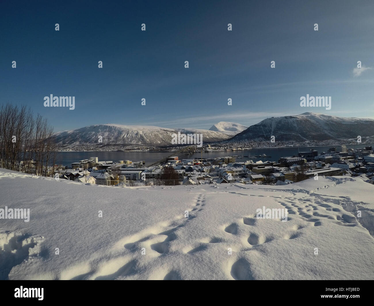 TROMSOE, Noruega - Marzo 4, 2017: la isla de la ciudad de Tromsoe video de visión general con tráfico de automóviles durante el puente de la isla de tromsoe, telón de fondo de montañas nevadas, cielo azul Foto de stock