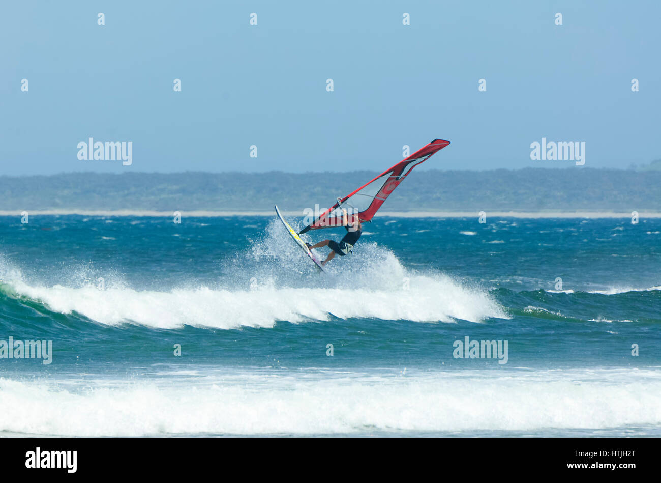 La windsurfista saltar por encima de una ola grande en Seven Mile Beach, Gerroa, Costa Illawarra, Nueva Gales del Sur (NSW, Australia Foto de stock