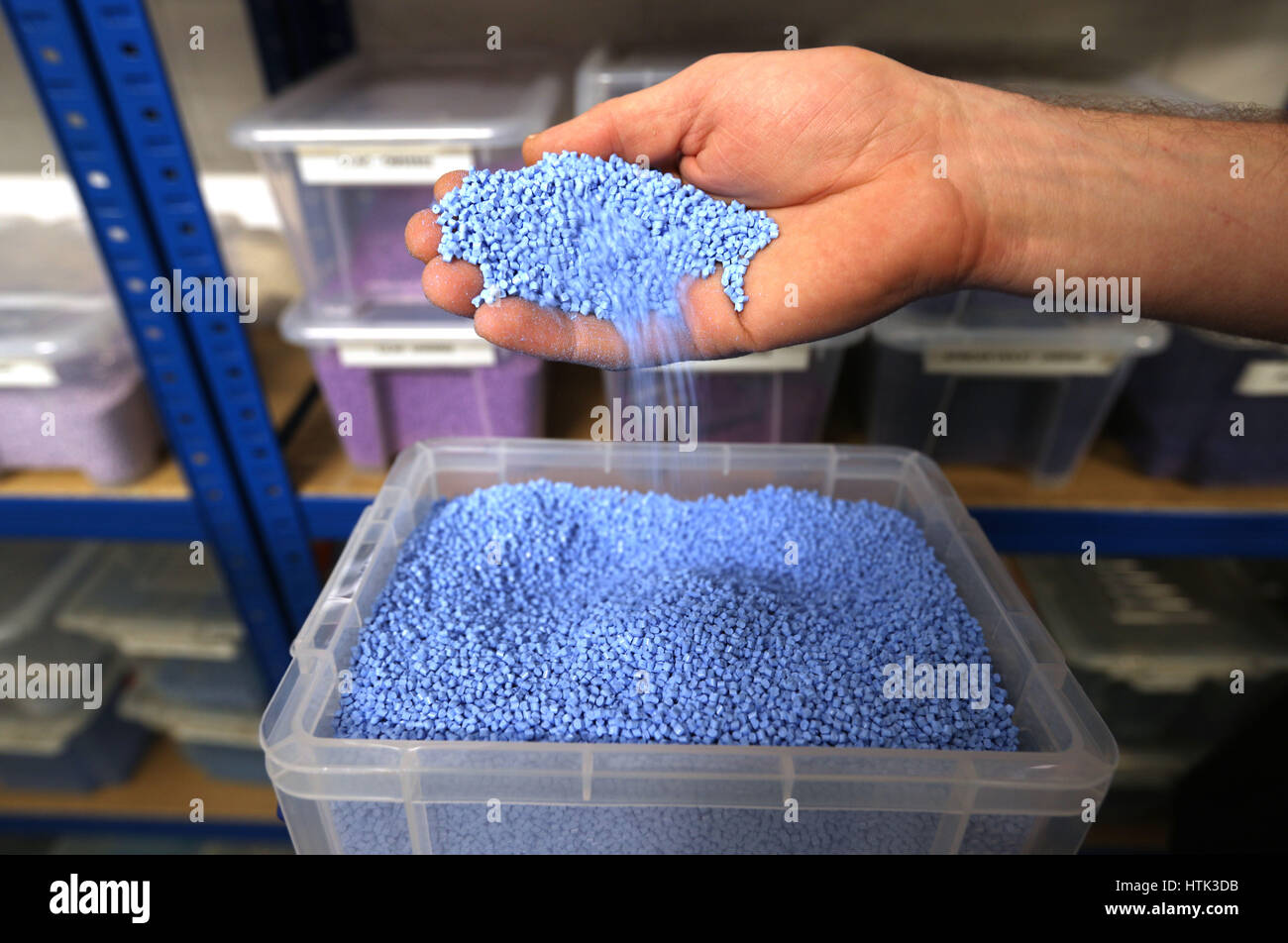 Una sala de prensa operativo agarra un puñado de bolitas de PVC azul hielo en la fábrica de Vinilo, Hayes, Middlesex. La mayoría de los pellets utilizados para crear la mezcla de discos de vinilo son claras y sólo un pequeño porcentaje de gránulos de color son necesarios para crear, en este caso, un disco de vinilo azul. Foto de stock