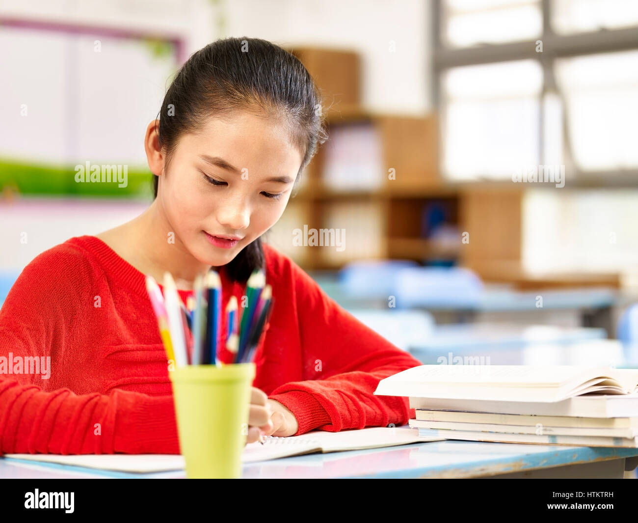 Asia alumna primaria estudiando en el aula. Foto de stock