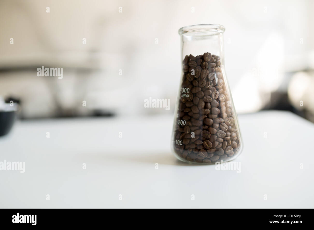 Los granos de café tostado oscuro sobre la mesa en un restaurante en vidrio Foto de stock