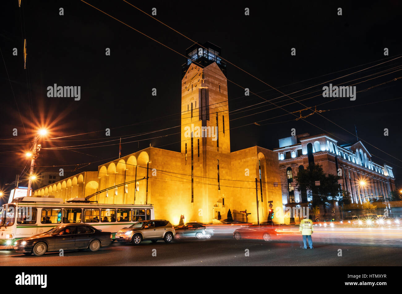 En Yerevan, Armenia - Octubre 24, 2016: Por la noche el tráfico con pointsman contra el Ayuntamiento de Ereván, en las luces de la noche. Hito de Armenia Foto de stock