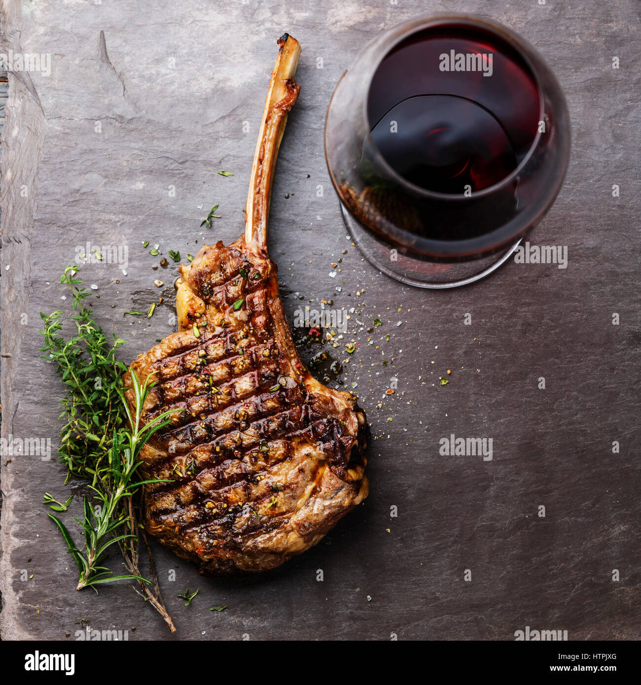 Parrillada de carne de ternera a la Parrilla Rib Steak en hueso y vino rojo sobre fondo de pizarra de piedra Foto de stock
