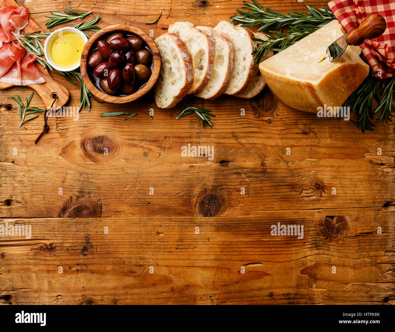 Comida italiana con jamón, rodajas de pan ciabatta, parmesano y aceitunas sobre fondo de madera espacio de copia Foto de stock