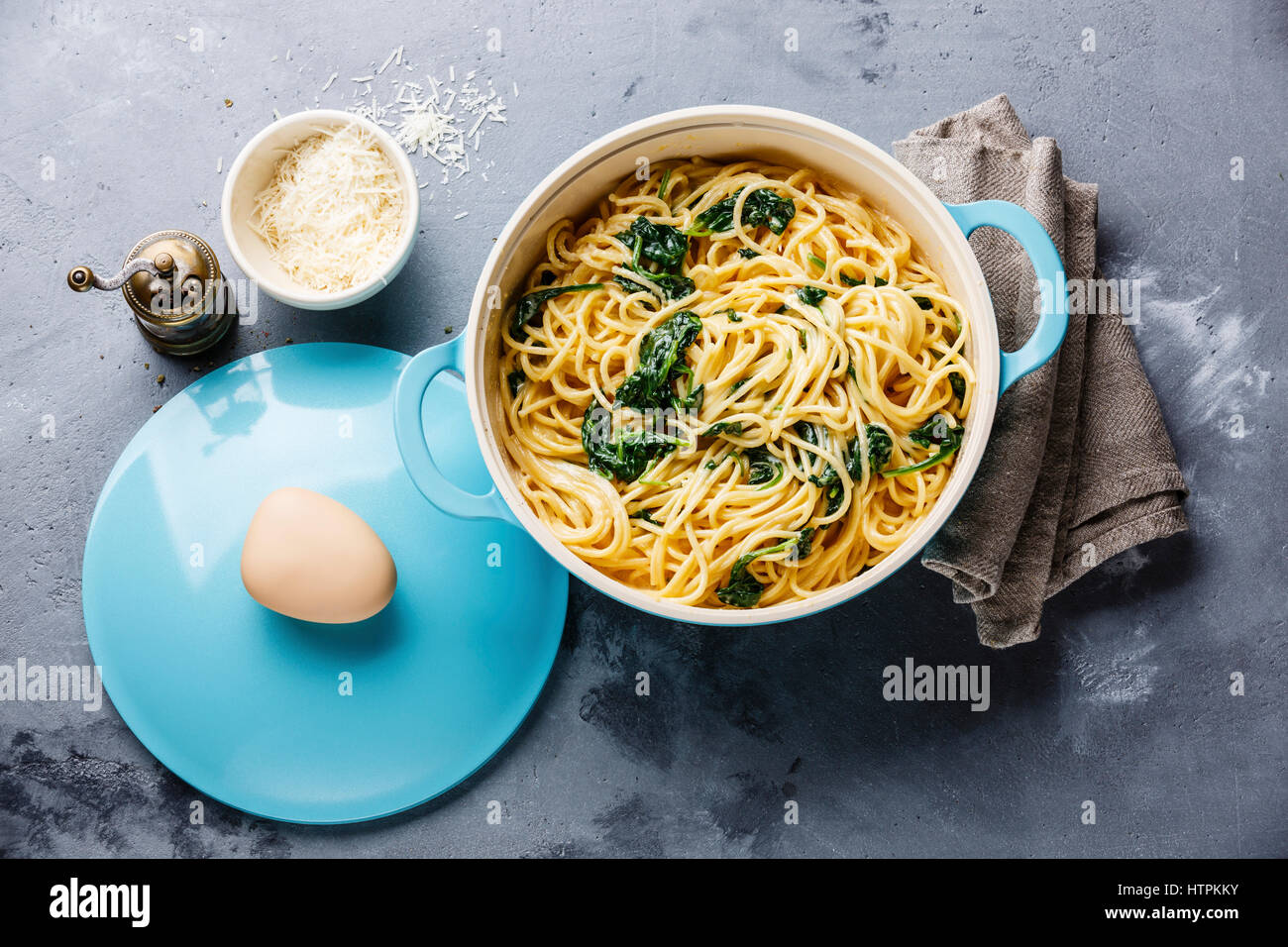 Espaguetis con espinacas y salsa de crema en la cacerola de fondo de hormigón gris Foto de stock