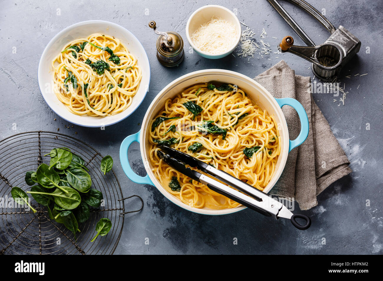 Espaguetis con espinacas y salsa de crema en la cacerola de fondo de hormigón gris Foto de stock