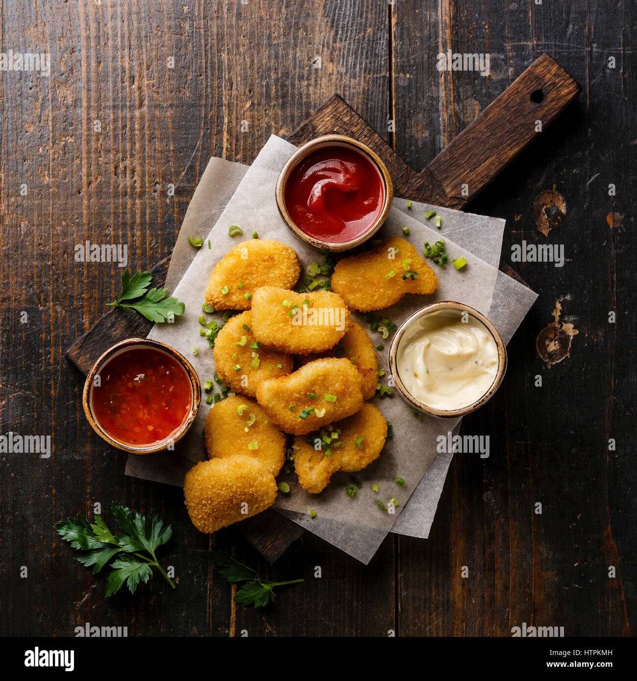 Nuggets de pollo con tres salsas de elección popular sobre fondo de madera Foto de stock
