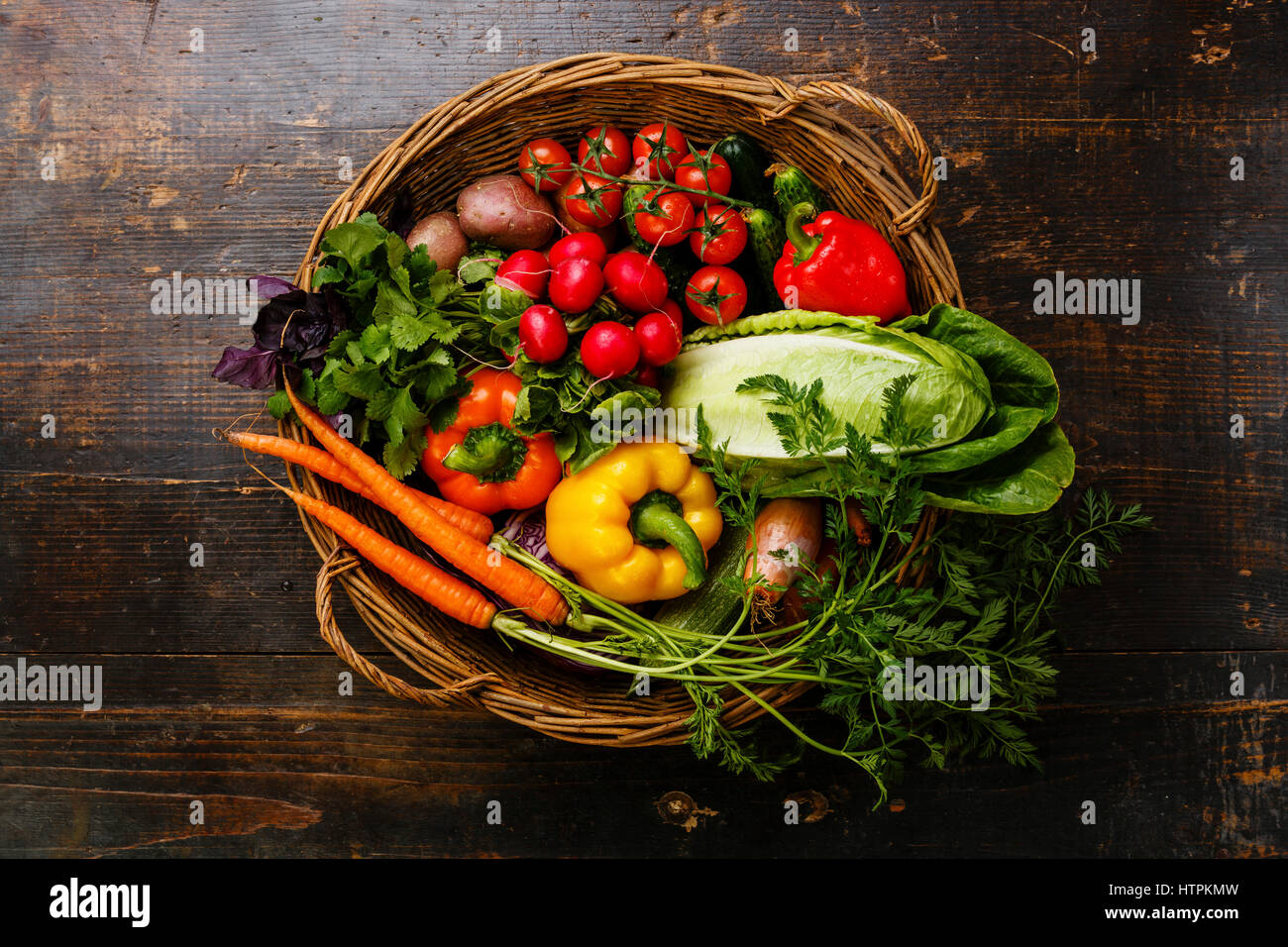 Hortalizas frescas en el canasto sobre fondo de madera Foto de stock